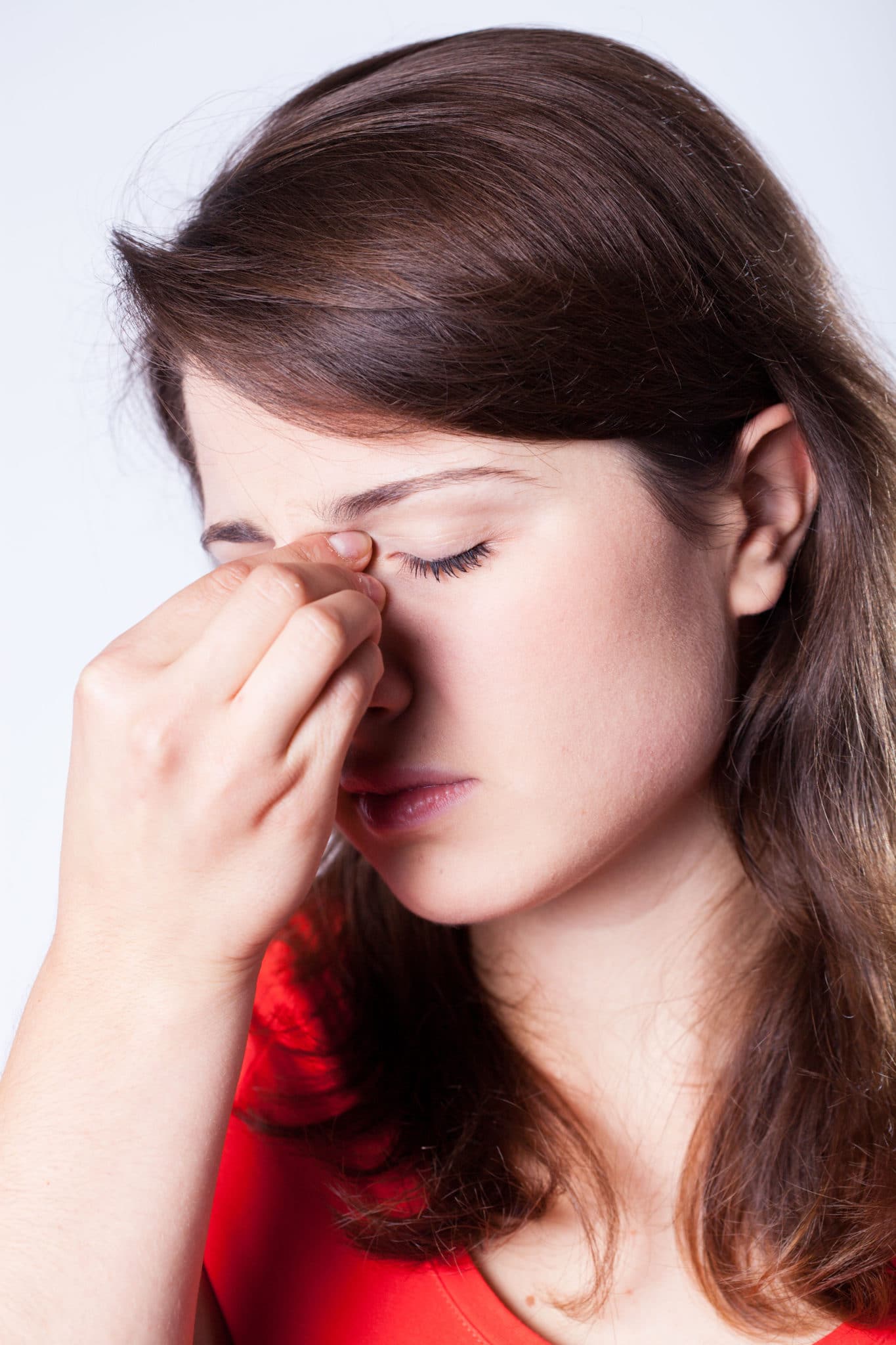 Woman pinching the bridge of her nose.